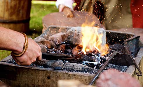 The image shows the heat and sparks from the blacksmiths forge while air is being blown through the bellows.