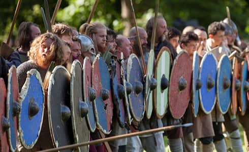The image shows a long line of warriors forming the shield wall with their weapons at the reading and preparing to march against their enemy.