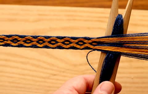 The weaving shuttle pasing the weft thread through the warp